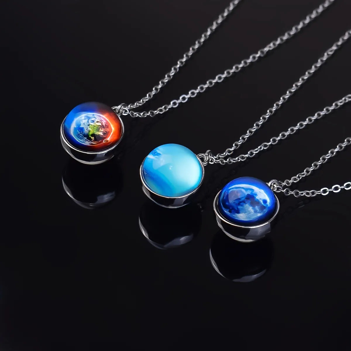 Three planet-themed necklaces on a black background