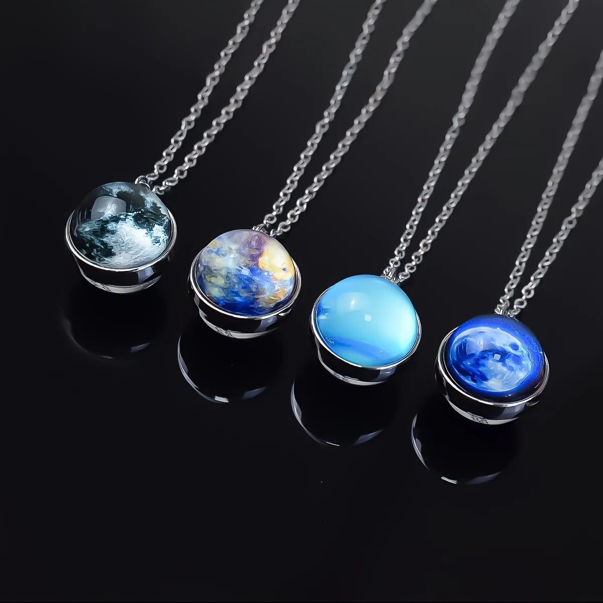 Four necklaces with spherical pendant designs on a black background